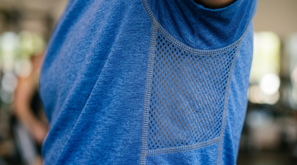 Close-up of a polyester exercise t-shirt showing breathable mesh fabric panels and flatlock seam stitching