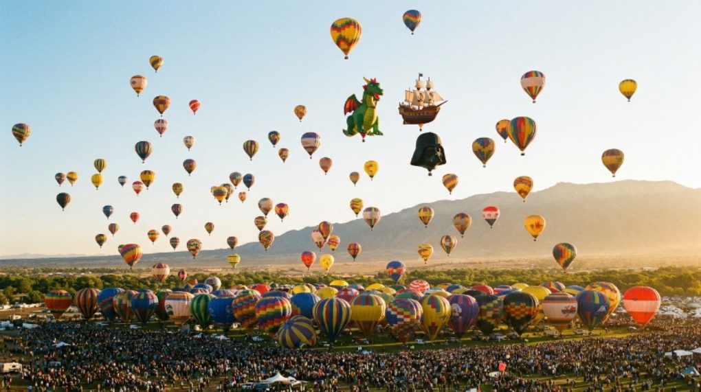 Hundreds of colorful hot air balloons lifting off during the Mass Ascension at Albuquerque International Balloon Fiesta at sunrise