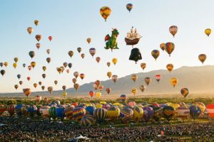 Hundreds of colorful hot air balloons lifting off during the Mass Ascension at Albuquerque International Balloon Fiesta at sunrise