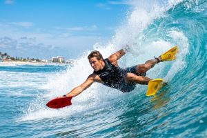 Surfer riding a Florida wave with a red handplane.