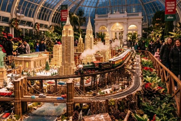 Model trains traveling past miniature New York City landmarks inside the Enid A. Haupt Conservatory at NYBG during the Holiday Train Show 2026