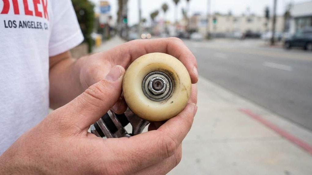 Skateboard wheels being inspected for slow rotation